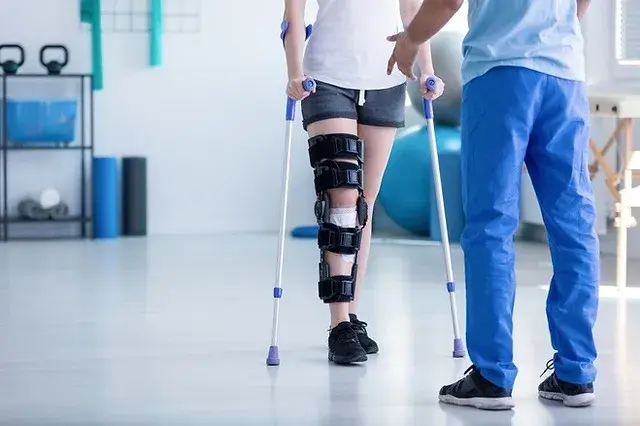 فردی که در بیمارستان قرار دارد و دکتر نیز در روبه رویش است و درحال فیزیوتراپی پای خپد میباشد که دستگاه به پایش متصل شده است