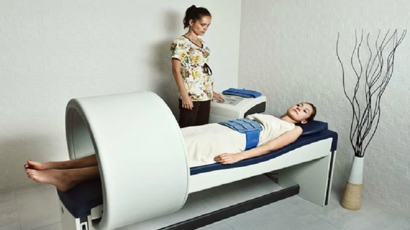 فردی که بر روی تخت دستگاه مگنت تراپی دراز کشیده است و دکتر نیز بالایی سرش قرار دارد