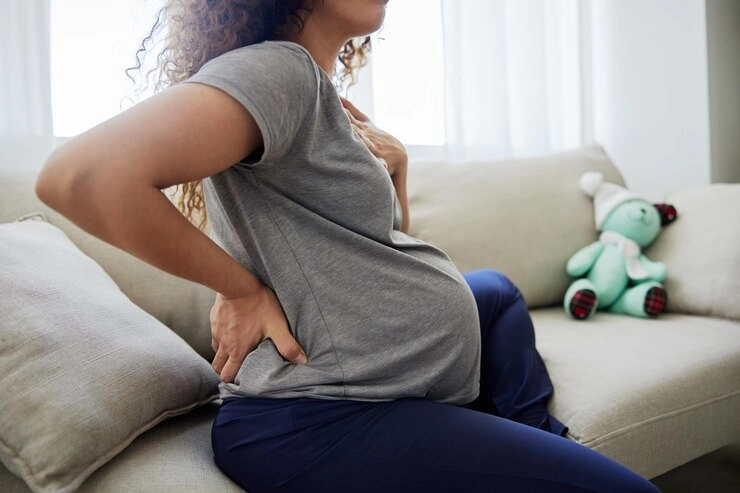 کمر درد بعد از زایمان - زن باردار نشسته بر روی مبل 