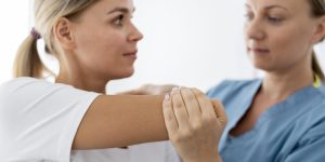 physiotherapist-helping-young-female-patient-her-clinic