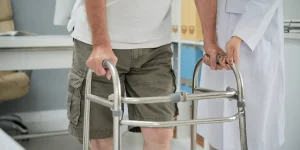 بیمار در حال تمرین راه رفتن با واکر تحت نظر متخصص توانبخشی پس از سکته مغزی