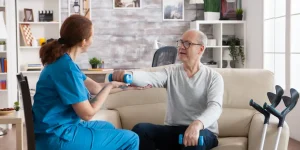 alt: توانبخشی سکته مغزی با فیزیوتراپی – تمرین بازتوانی اندام فوقانی با دمبل برای آقای سالمند